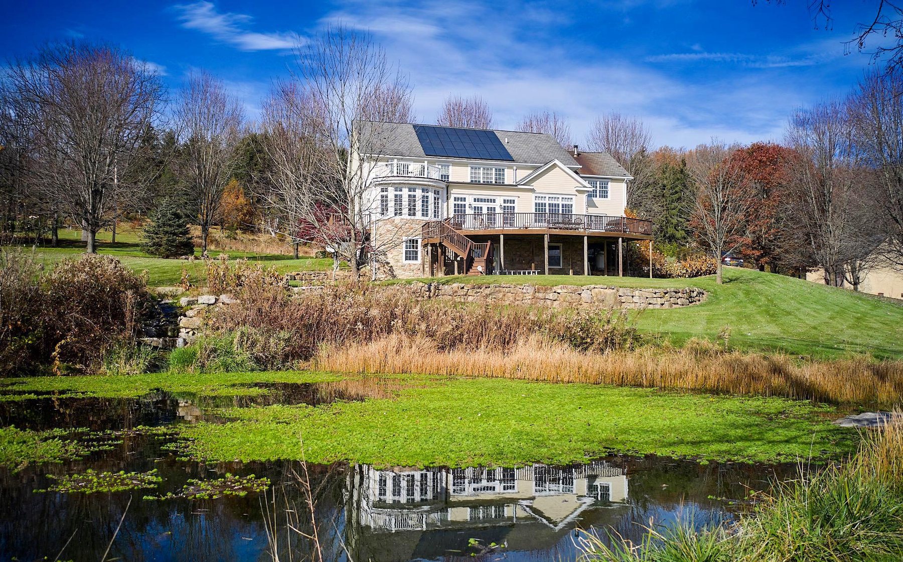 1400 County Line Road, a home above a pond with autumn trees